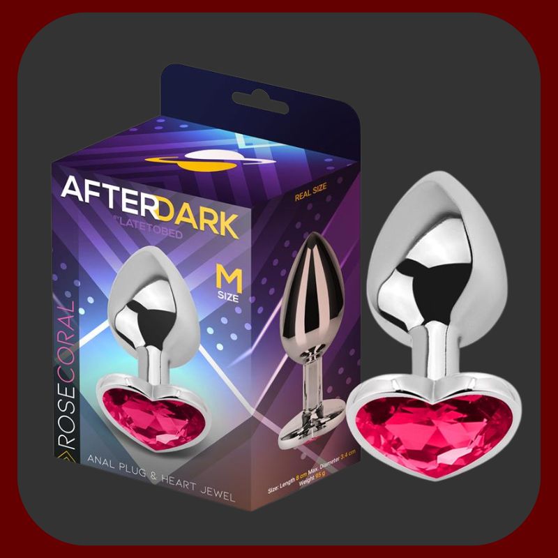 Eroriana – anální kolík Afterdark velikosti M s hladkým růžovým korálovým povrchem a srdíčkovou základnou s rubínovým kamenem. Ergonomický tvar pro pohodlnou a bezpečnou stimulaci prostaty, ideální pro pokročilé uživatele.