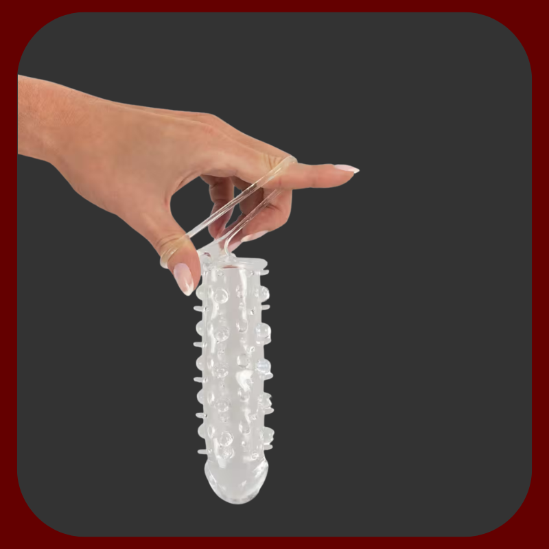 Návlek na penis z pružného silikonu s kroužkem na varlata a stimulačními výstupky. Průhledný design, zvětšení délky o 2 cm.