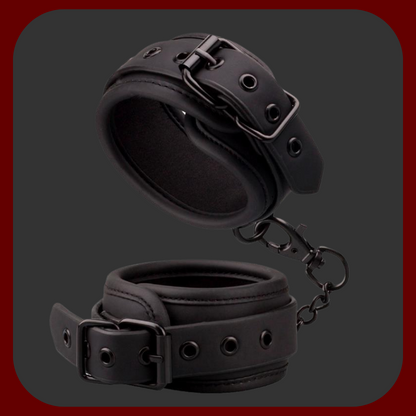 Nastavitelné BDSM pouta z černé veganské ekokůže s kovovým řetízkem bez niklu. Vhodné pro použití na zápěstí i kotníky, s polstrovaným vnitřkem pro pohodlné nošení.