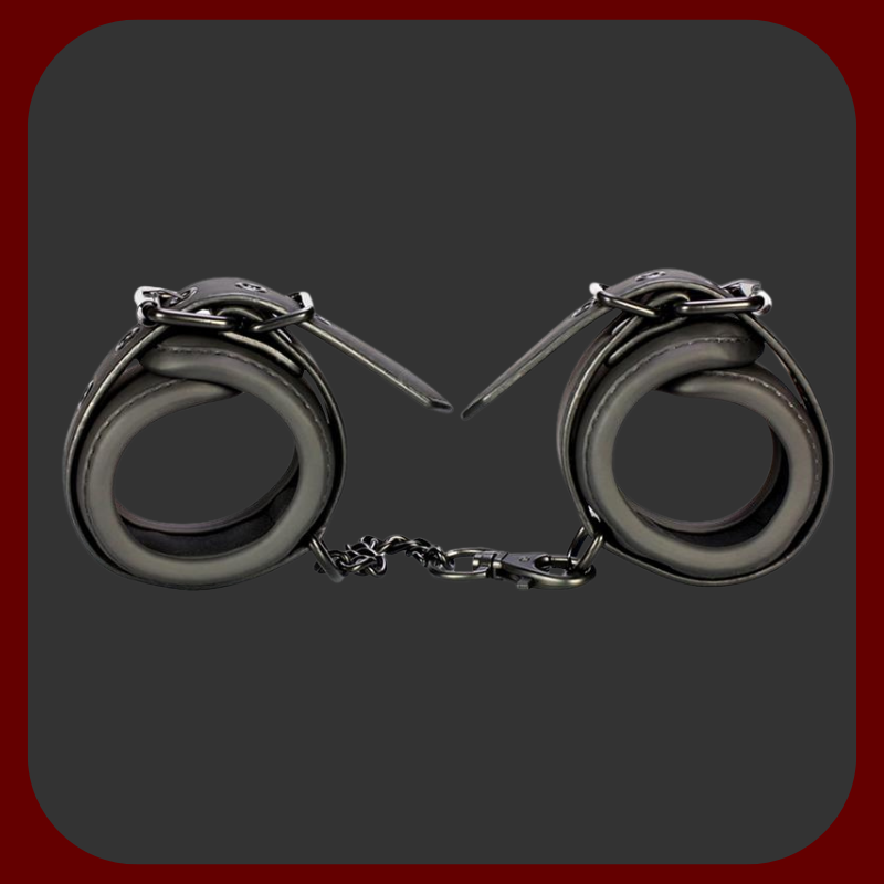 Nastavitelné BDSM pouta z černé veganské ekokůže s kovovým řetízkem bez niklu. Vhodné pro použití na zápěstí i kotníky, s polstrovaným vnitřkem pro pohodlné nošení.